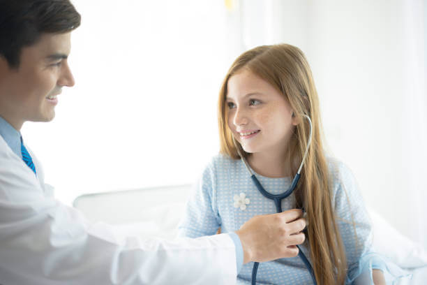 Little girl at the doctor for a checkup and listening to own heartbeat with stethoscope at medical office