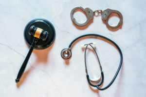 On a marble background, a judge's hammer next to some exhibits and a stethoscope