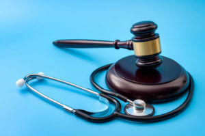 Healthcare legislation and regulation, medical malpractice decision and health care injury personal attorney concept with gavel and stethoscope isolated on blue background