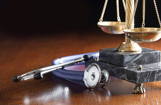 Stethoscope and Scales of Justice on wood table with copy space