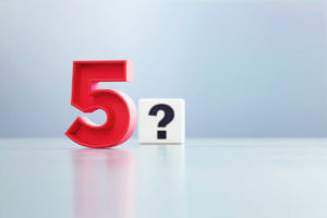 Red Number 5 And Question Mark Written White Cube Sitting Before Defocused Background