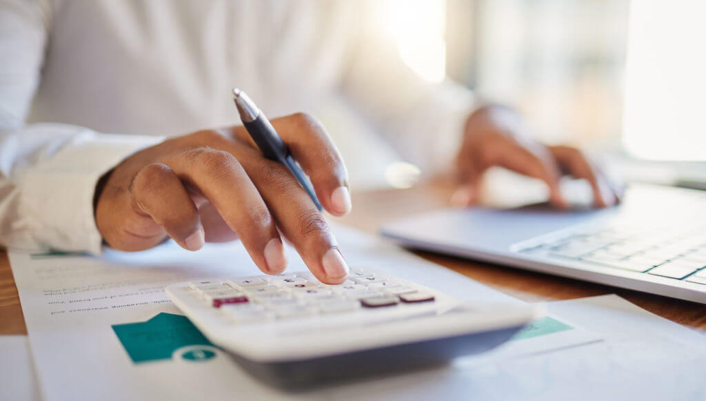 a man on a computer and calculator working out his business budget strateg