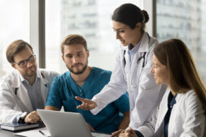 A female doctor is discussing malpractice insurance costs with her colleagues in the medical field.