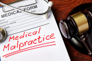 A medical form with words Medical Malpractice and gavel.