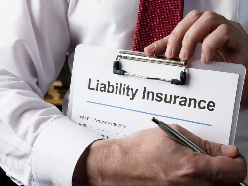 Hands hold liability insurance policy and pen